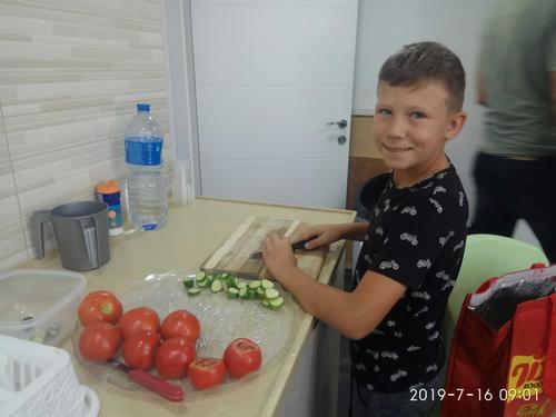 ילד חותך עגבניה ומלפפון בשביל ארוחת הבוקר