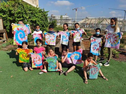 פעילות צביעת חולצות. ילדים מציגים את החולצות שצבעו