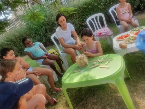ילדים משחקים ג'אנגה (משחק קופסה פופולרי) על הדשא ליד הבריכה